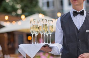 Catering service waiter holding a tray with glasses of Italian and French wine prosecco and champagne for tasting